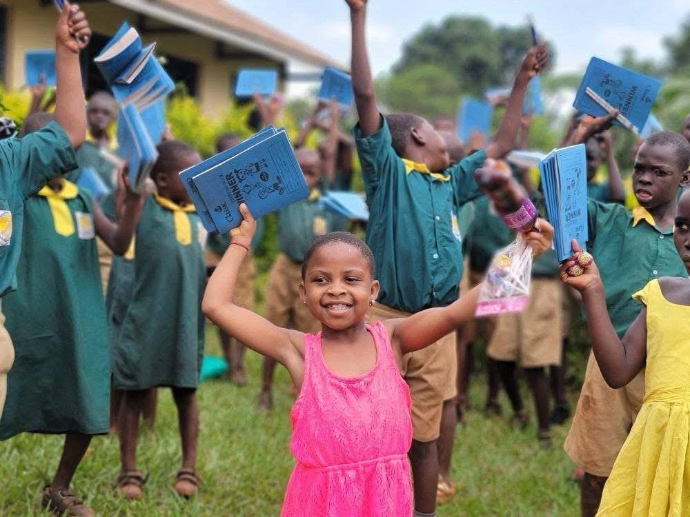 Ugandan school children celebrating with donated books from Refine Outreaches